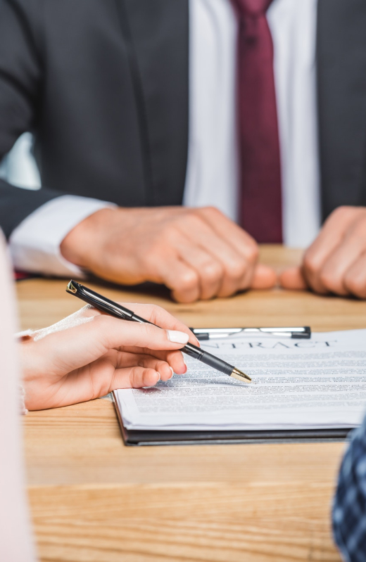 partial view of woman pointing at contract on table at lawyers office